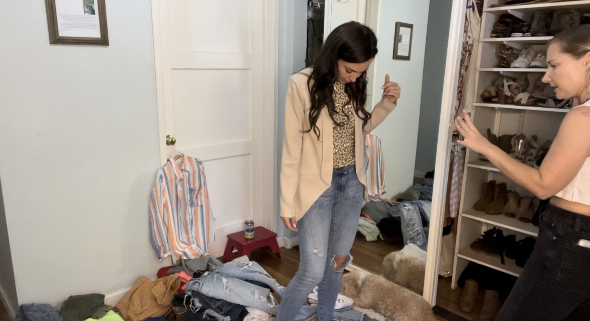 Woman looking down at her outfit in front of another woman