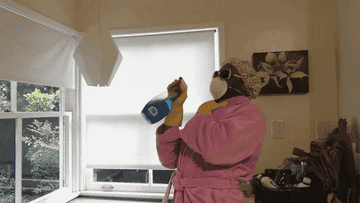 Man wearing mask and gloves and spraying cleaning supplies