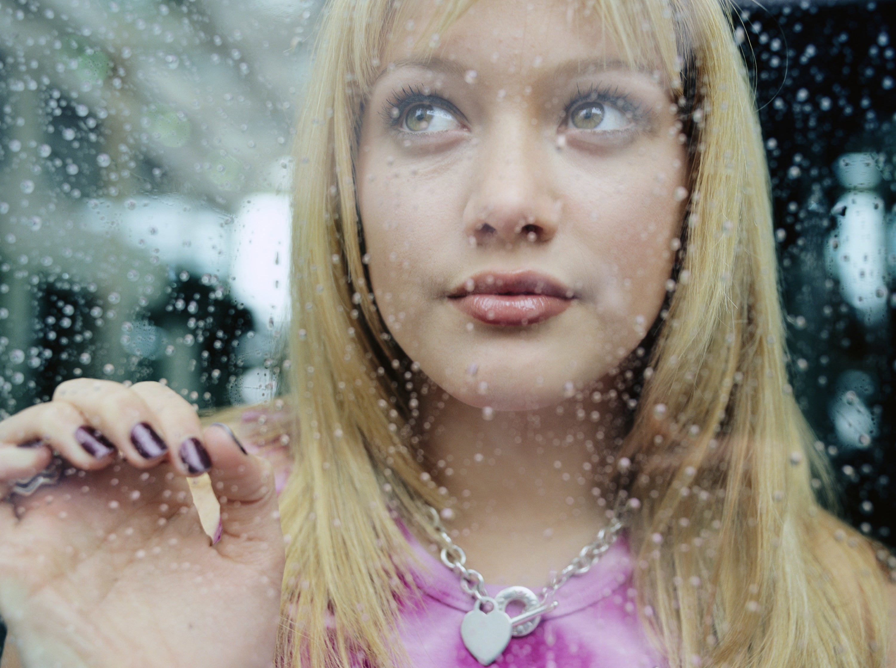 Hilary Duff looks out a rain-covered window