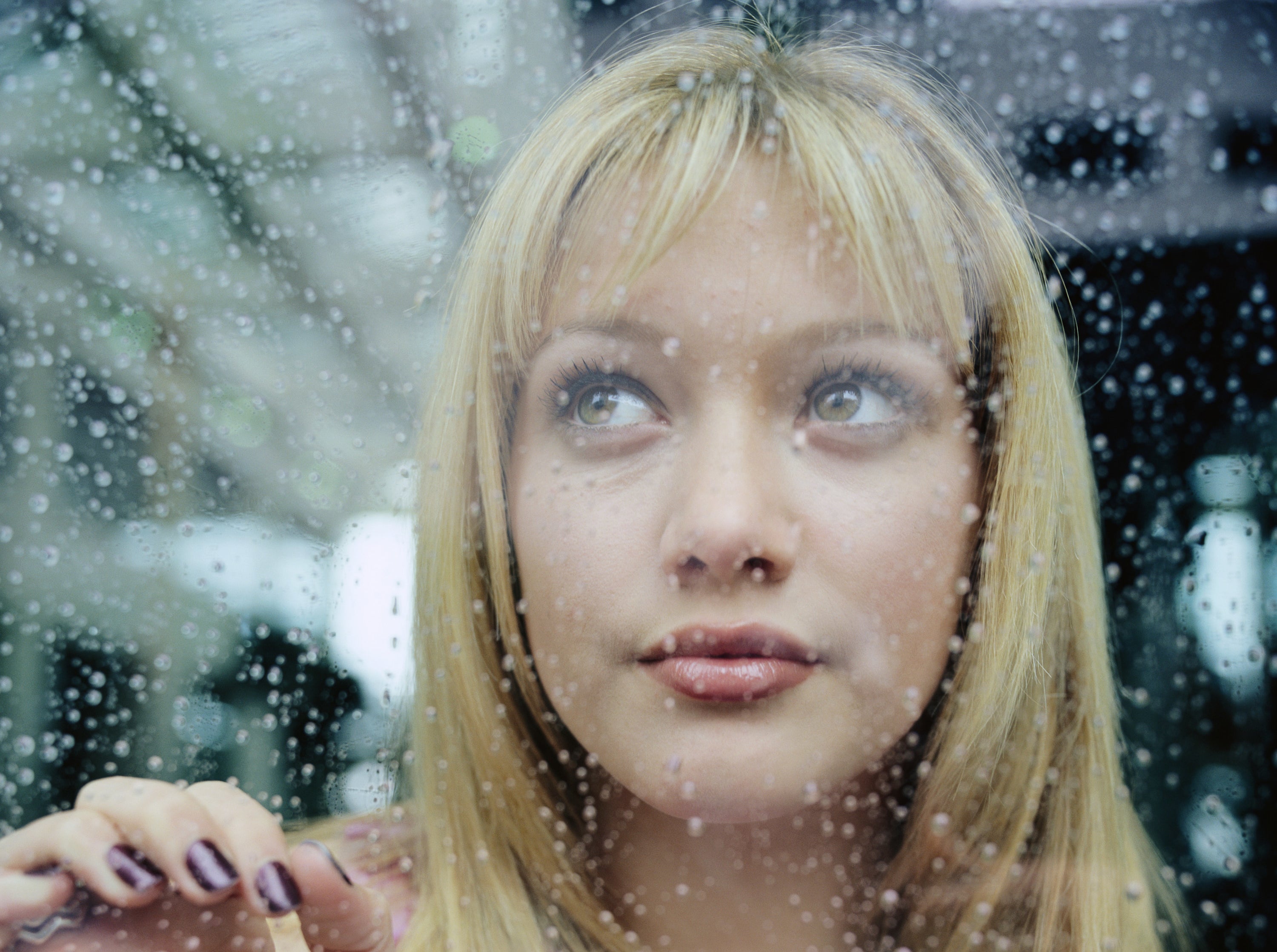 Hilary Duff looks out a rain-covered window