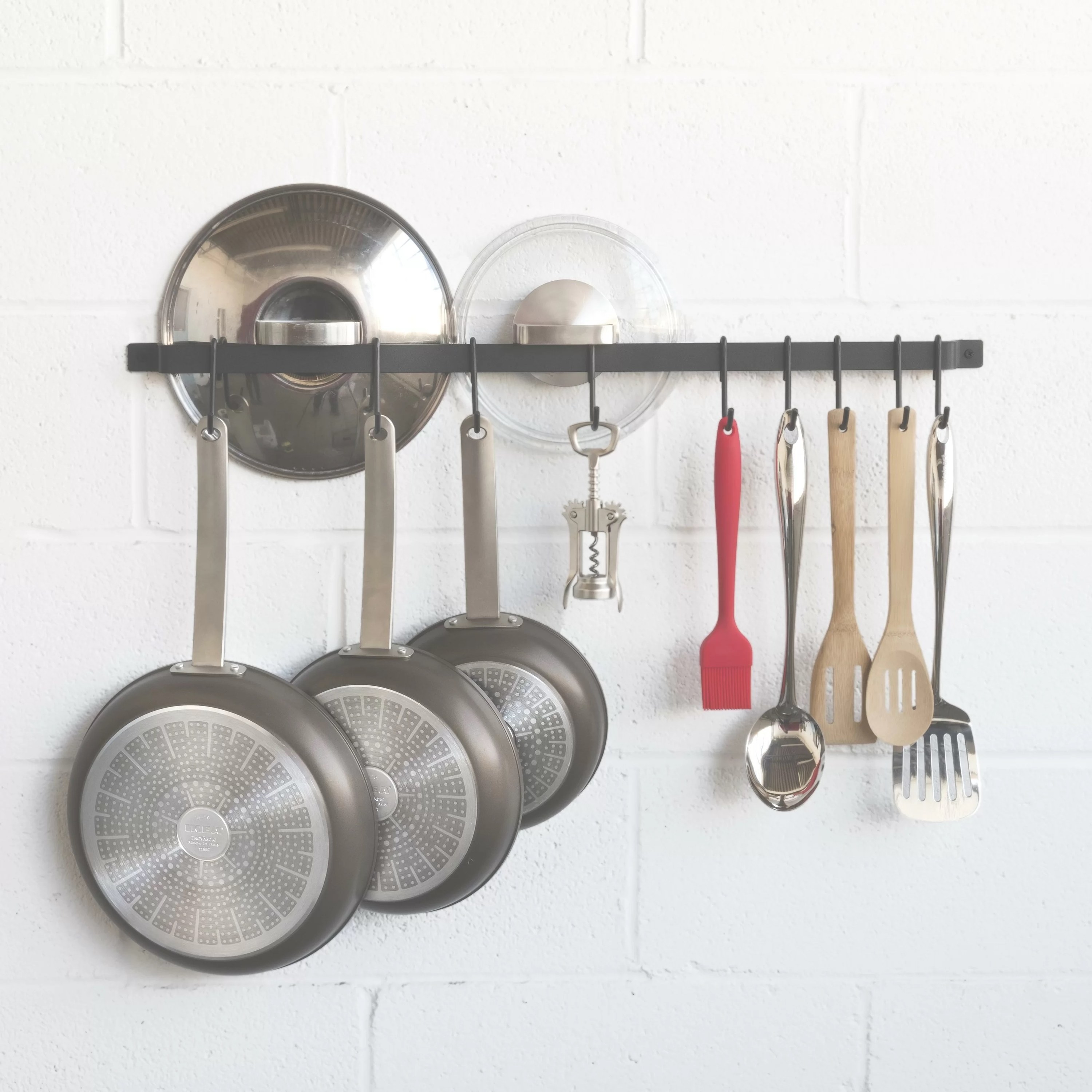 a pot rack holding pots, utensils, in a kitchen