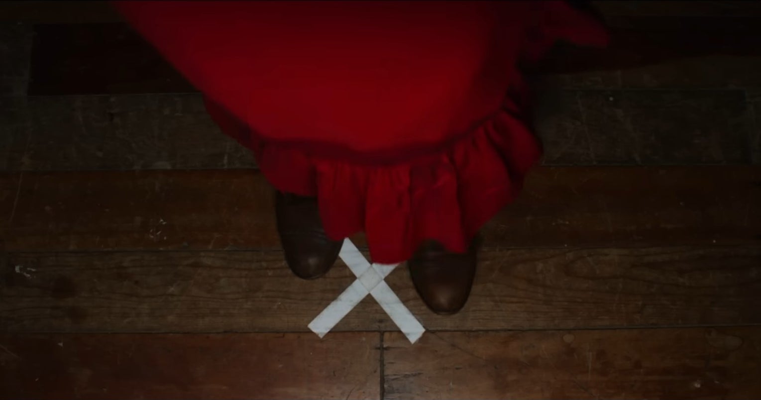 Pearl in a red dress stands on a white &quot;X&quot;.
