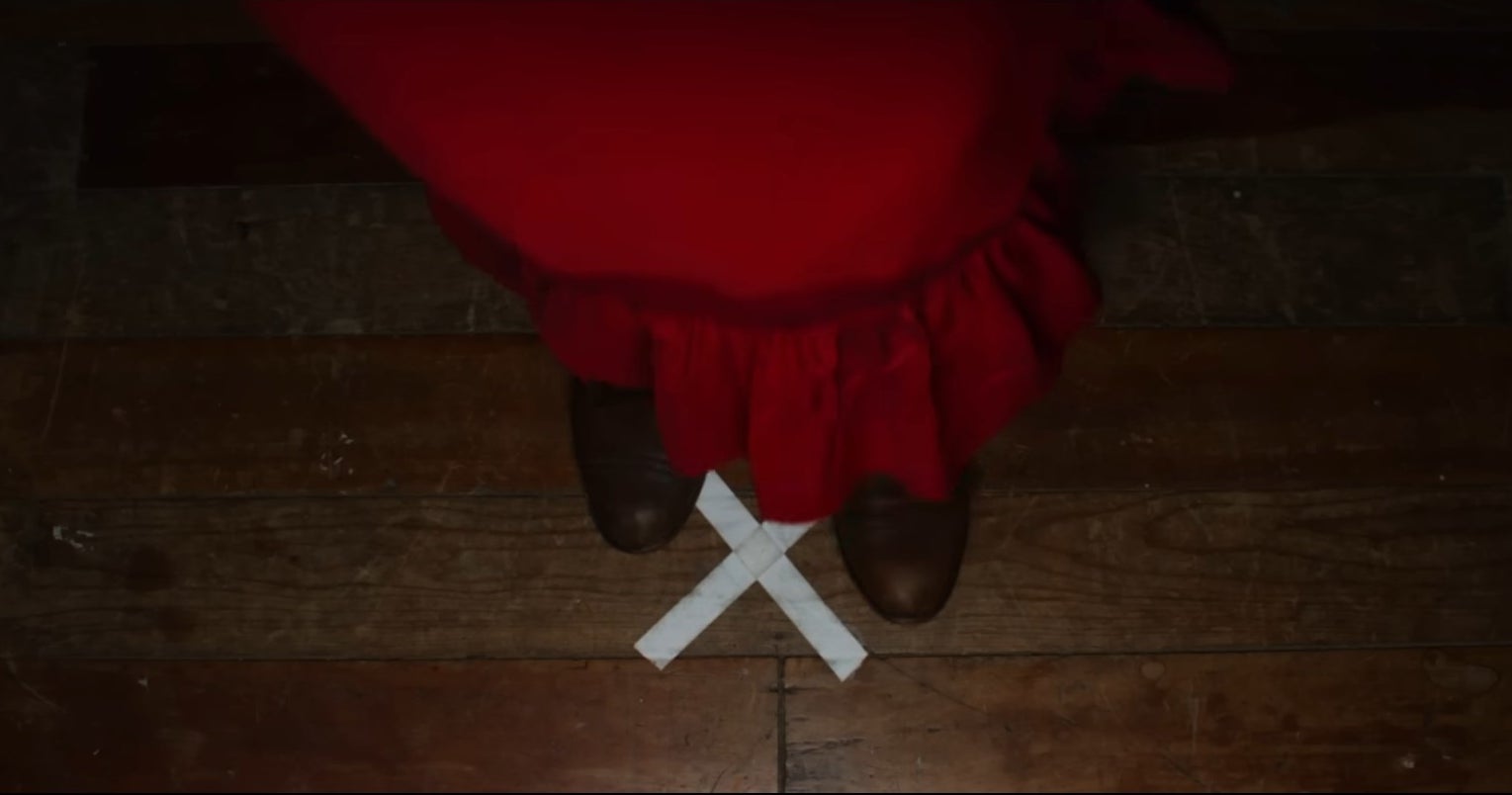 Pearl in a red dress stands on a white &quot;X&quot;.