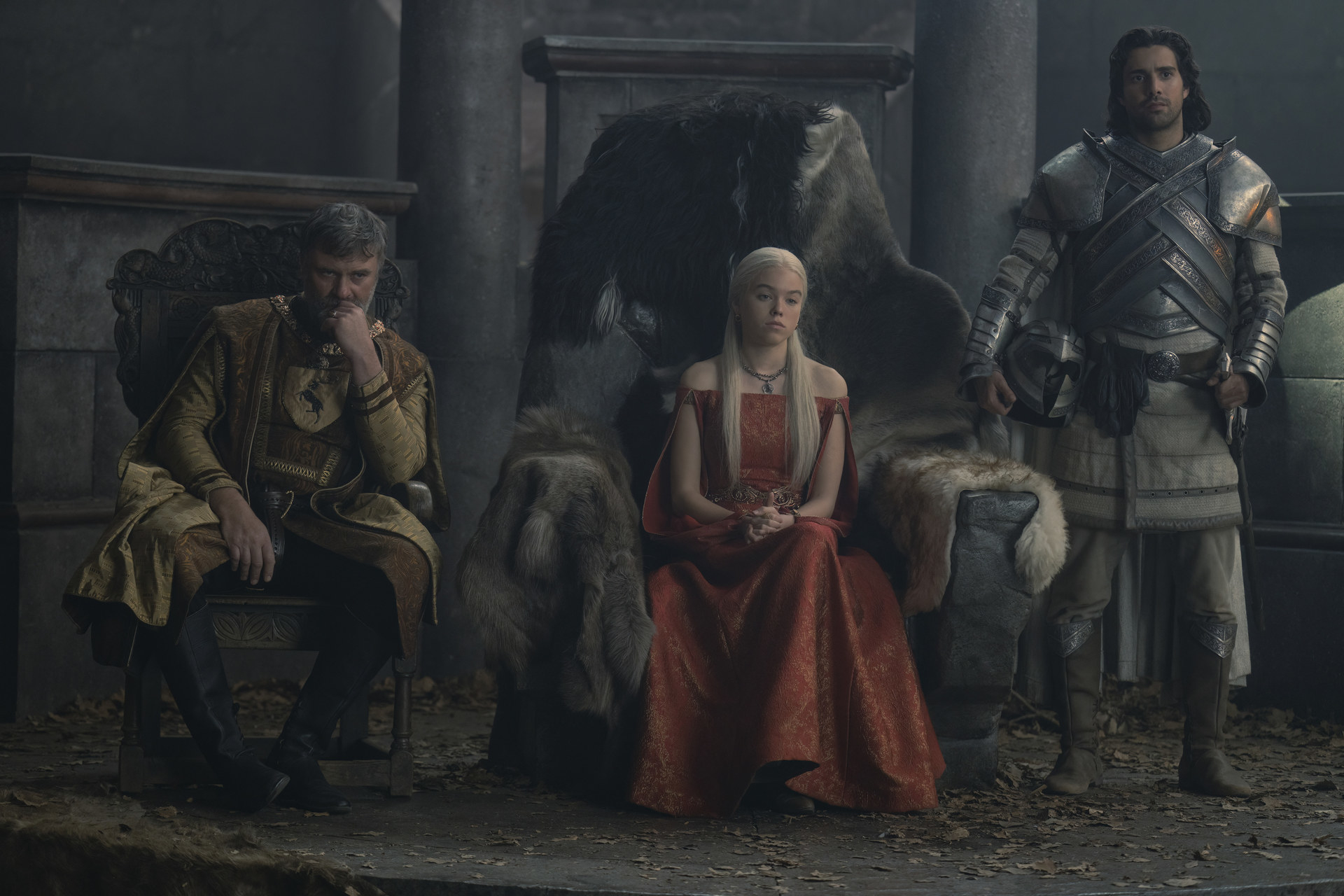 Rhaenyrs sits between Boremund Baratheon and Criston Cole wearing a red off-the-shoulder dress