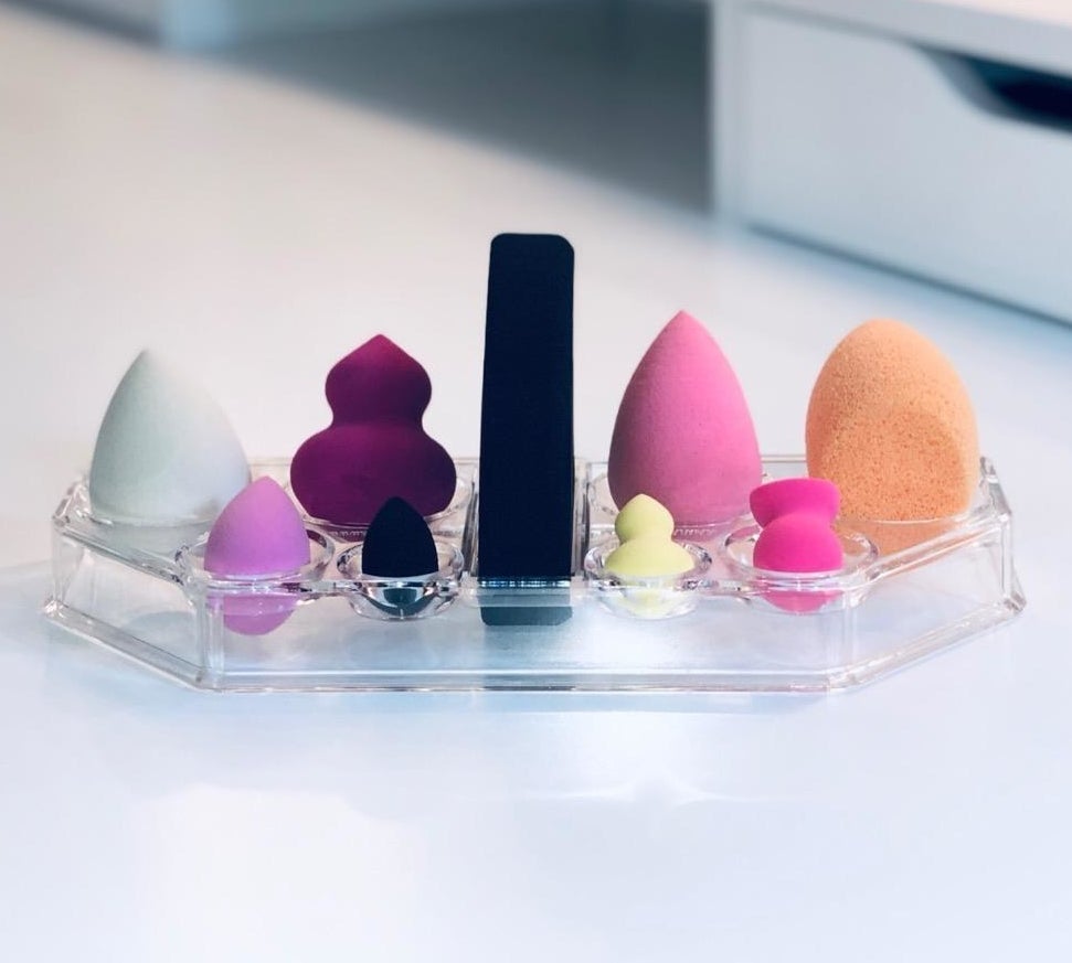 several sponges of different shapes and colors resting in the clear makeup sponge organizer