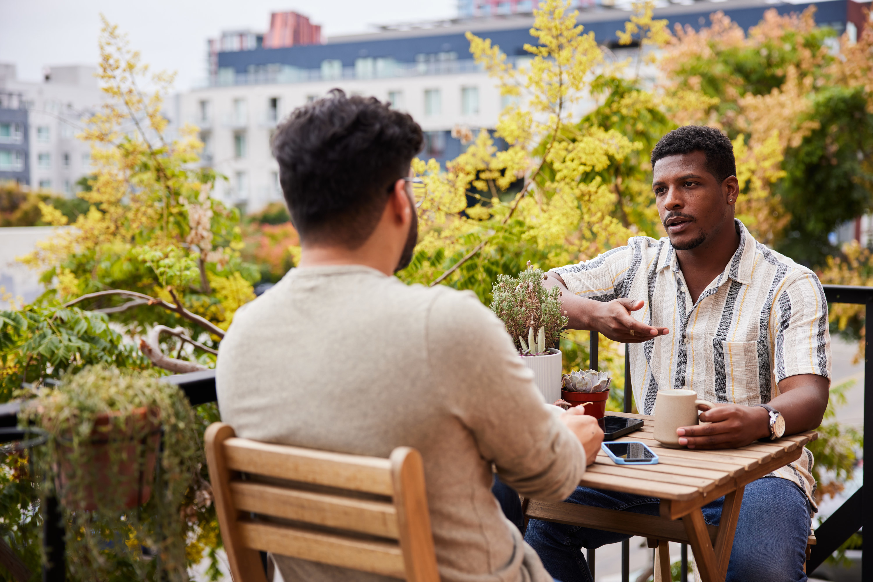 a couple talking outside while they drink coffee