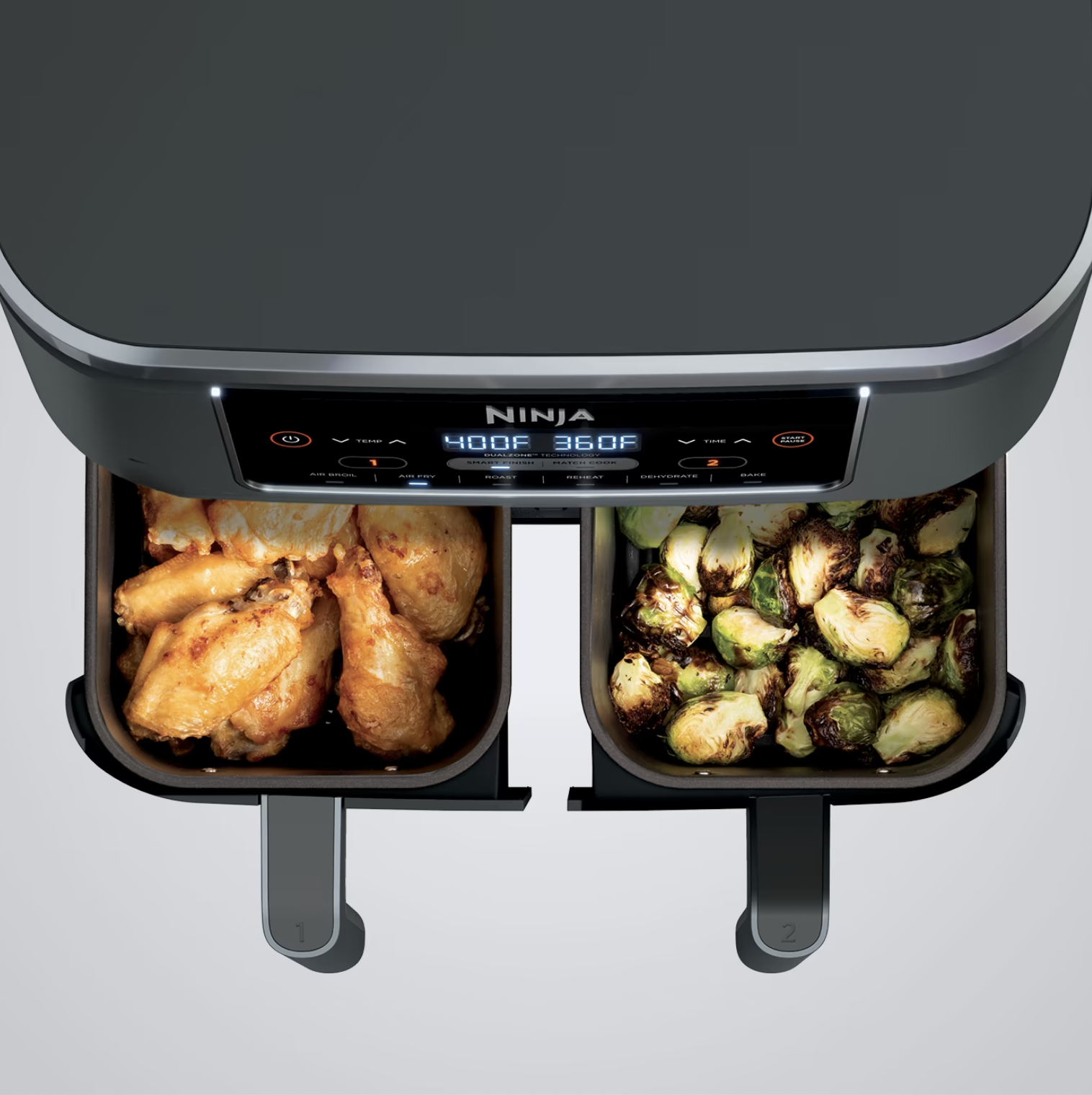 The air fryer baskets filled with brussels sprouts and chicken fingers