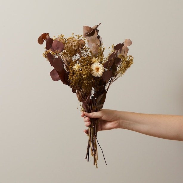 a person holding up a bouquet of dried flowers
