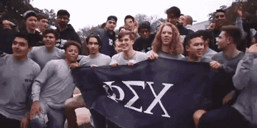 a group of fraternity brothers posing with a flag