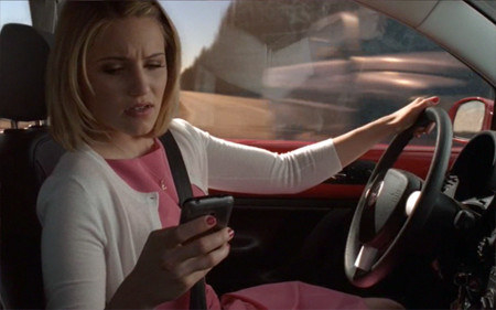 A character looking at her phone while driving