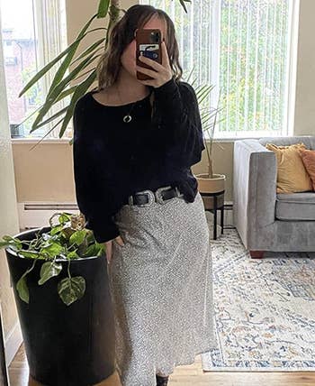 reviewer wearing belt over a skirt with a black top