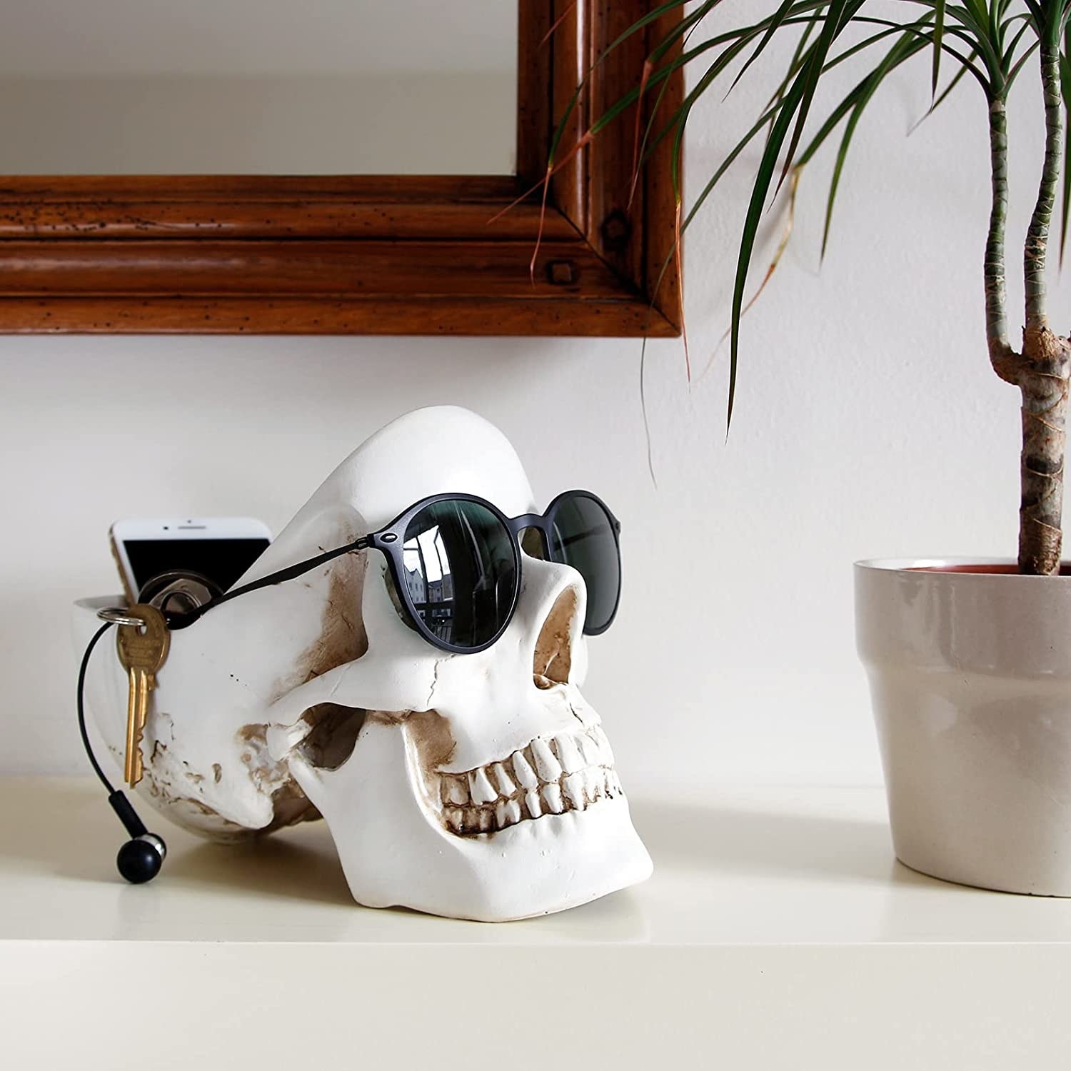 a skull-shaped trinket dish with a phone inside and a pair of sunglasses left on the face