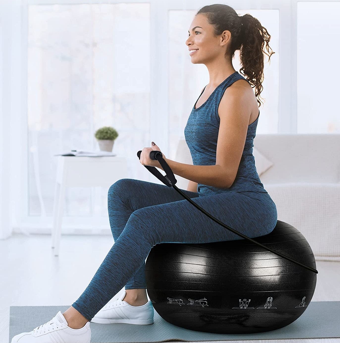 a person sitting on the exercise ball while holding a resistance band