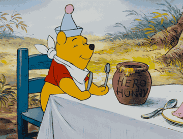 winnie the pooh sitting at a table dancing about to eat honey