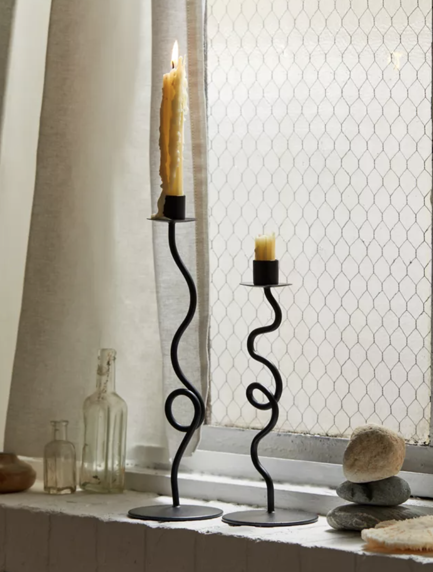 a pair of dark curly candle holders with drippy wax all over them