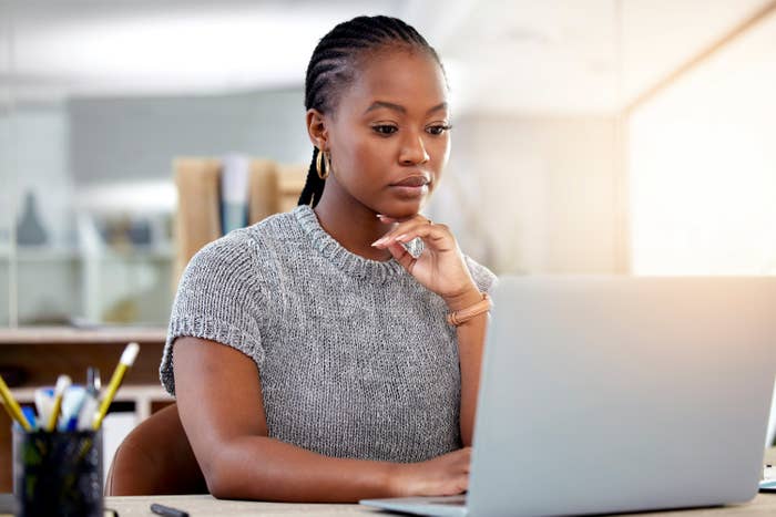A woman sits at her desk and works on her laptop