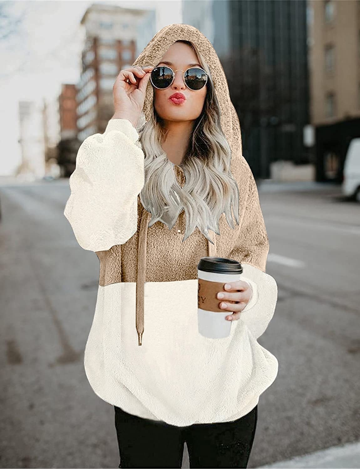 a person wearing the hoodie while standing outside with a cup of coffee
