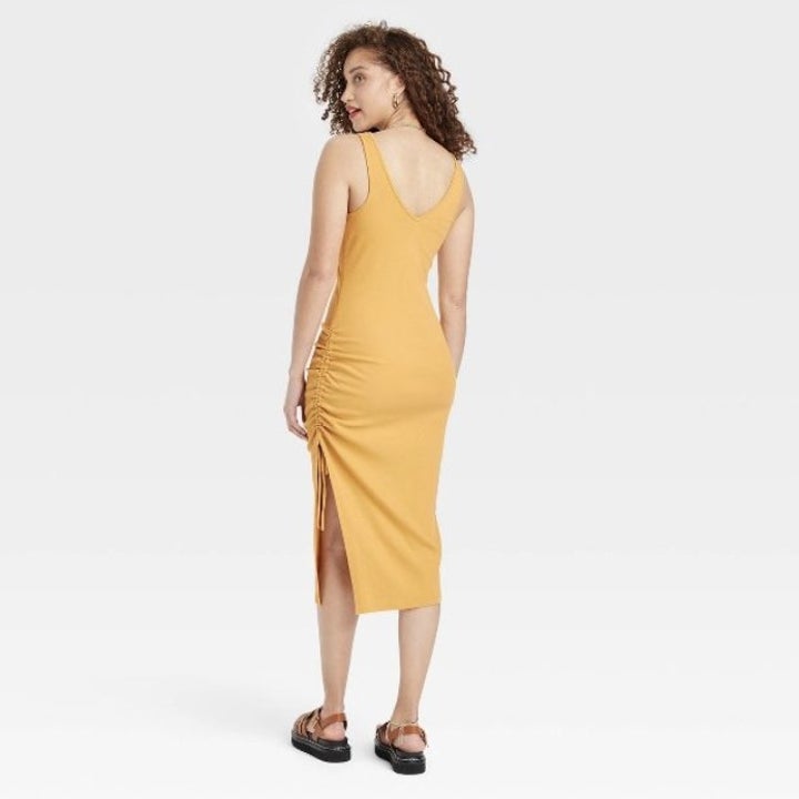 The model shows the yellow ruched dress from the back