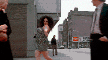 A person in drag dances down a street