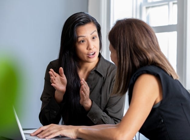 Two women share a discussion at work