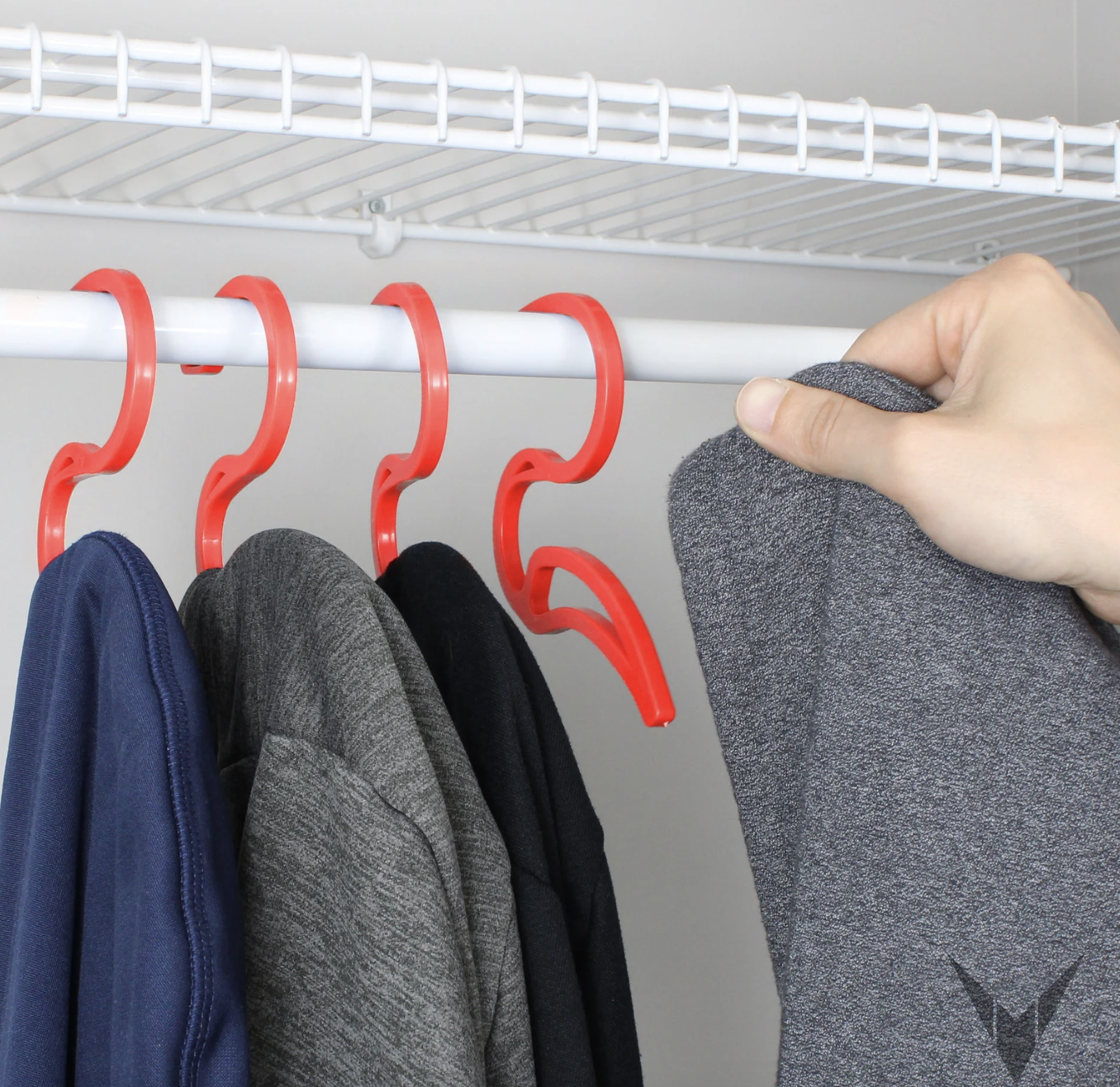 a hand hanging a hoodie on one of the hoodie hangers