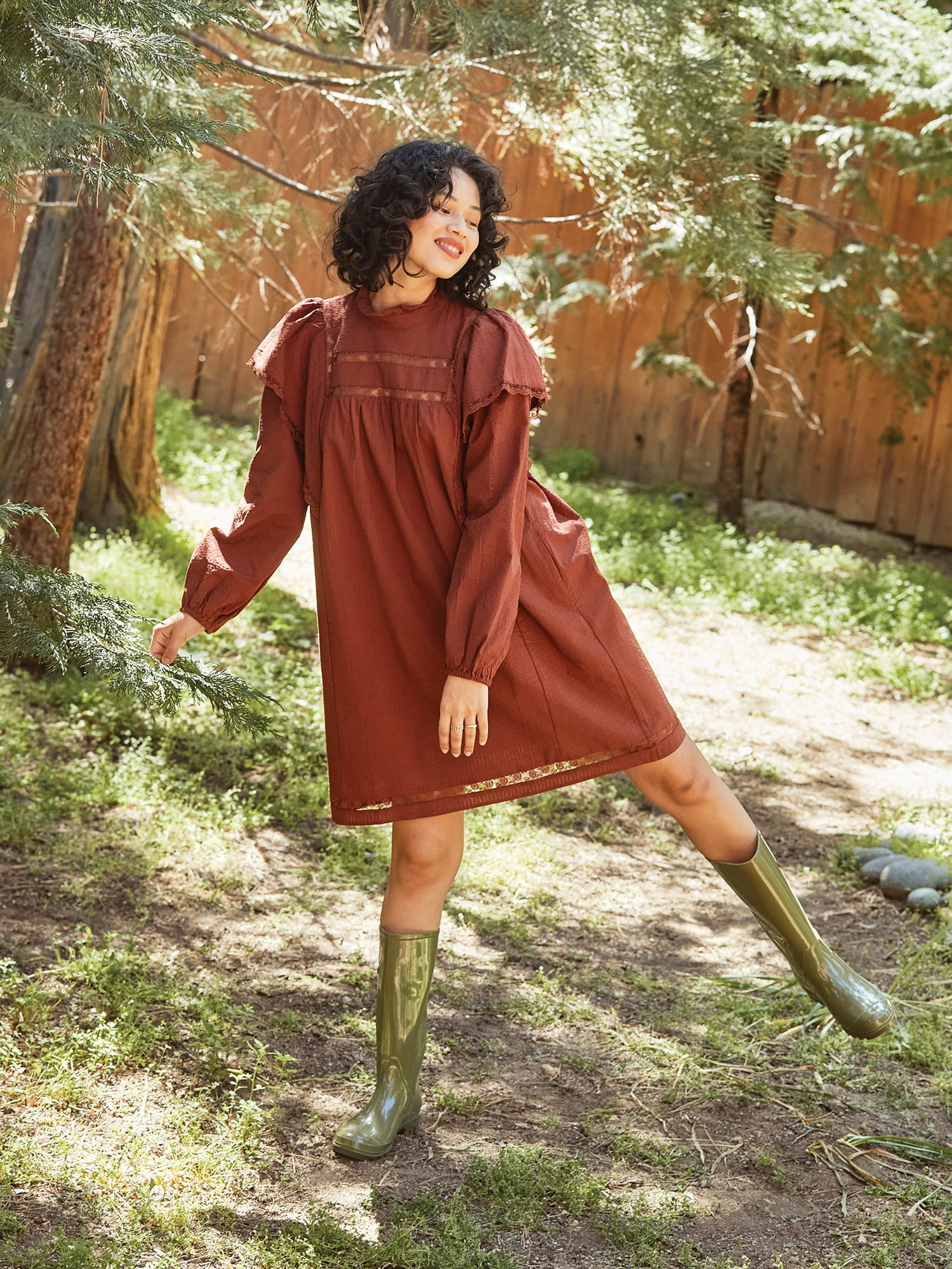 a model wearing the brown dress with green galoshes