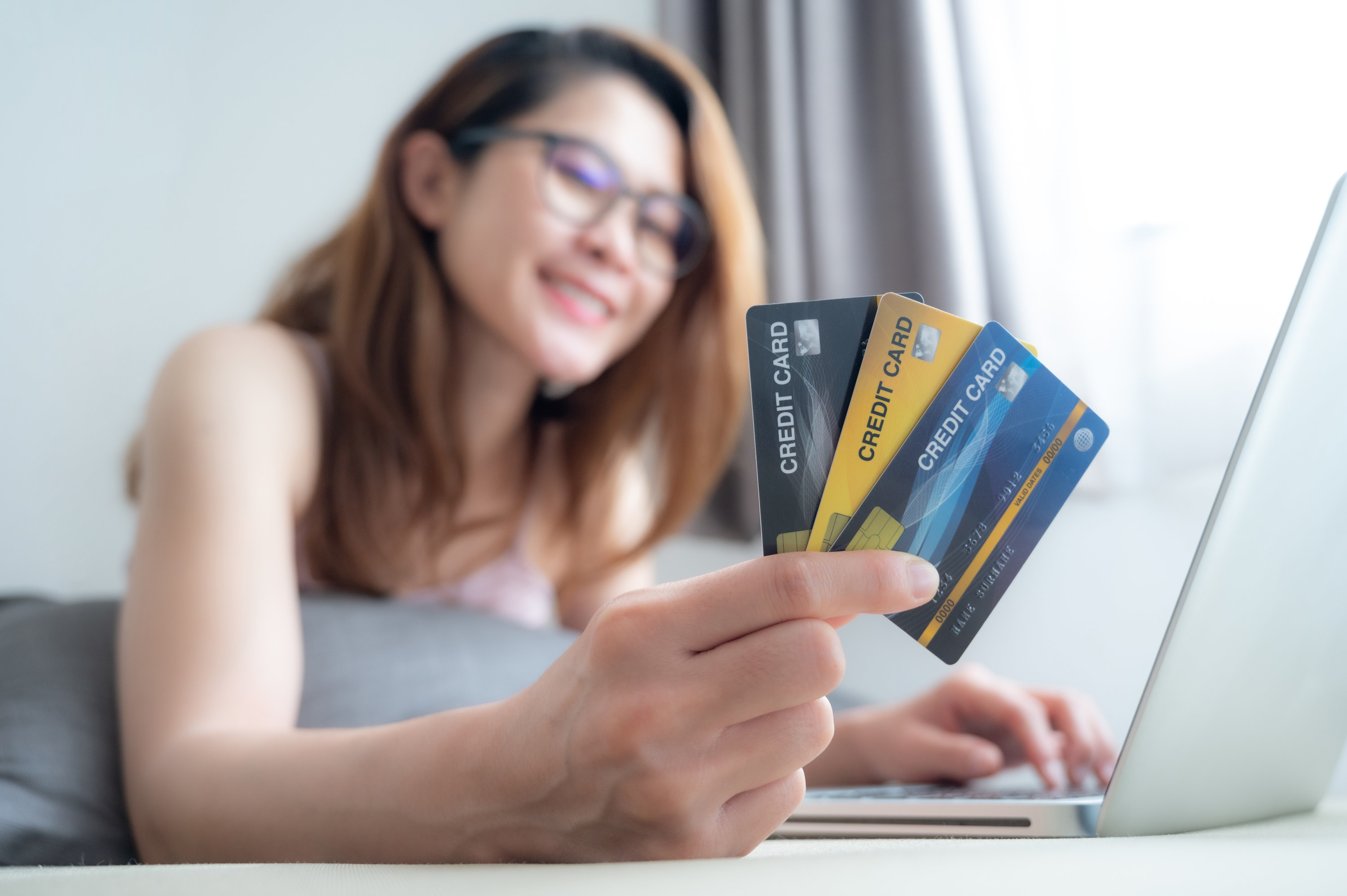 young woman holding three different credit cards