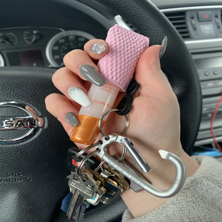 reviewer holds set of keys with attached pink lip balm holder on keychain