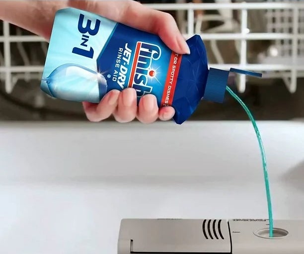 Bottle of rinse agent being poured into dishwasher