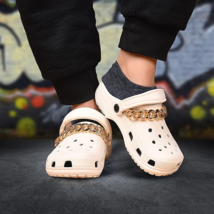 A person wearing Crocs with chains on them