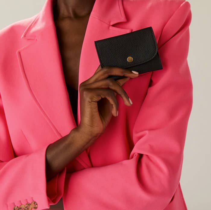 A person wearing a blazer holding up the cardholder