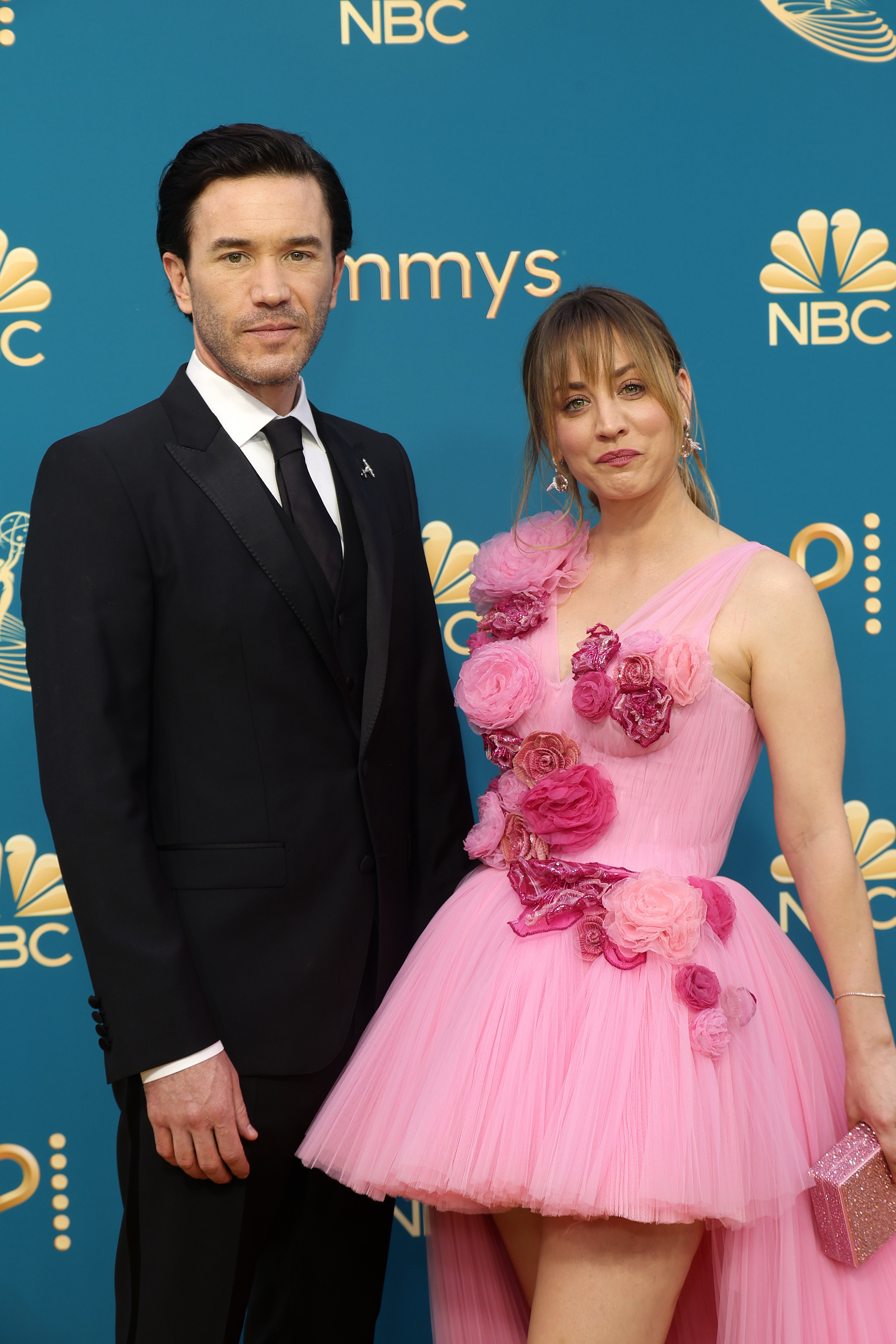 Tom Pelphrey in a black suit and Kaley Cuoco in a short pink dress with a train