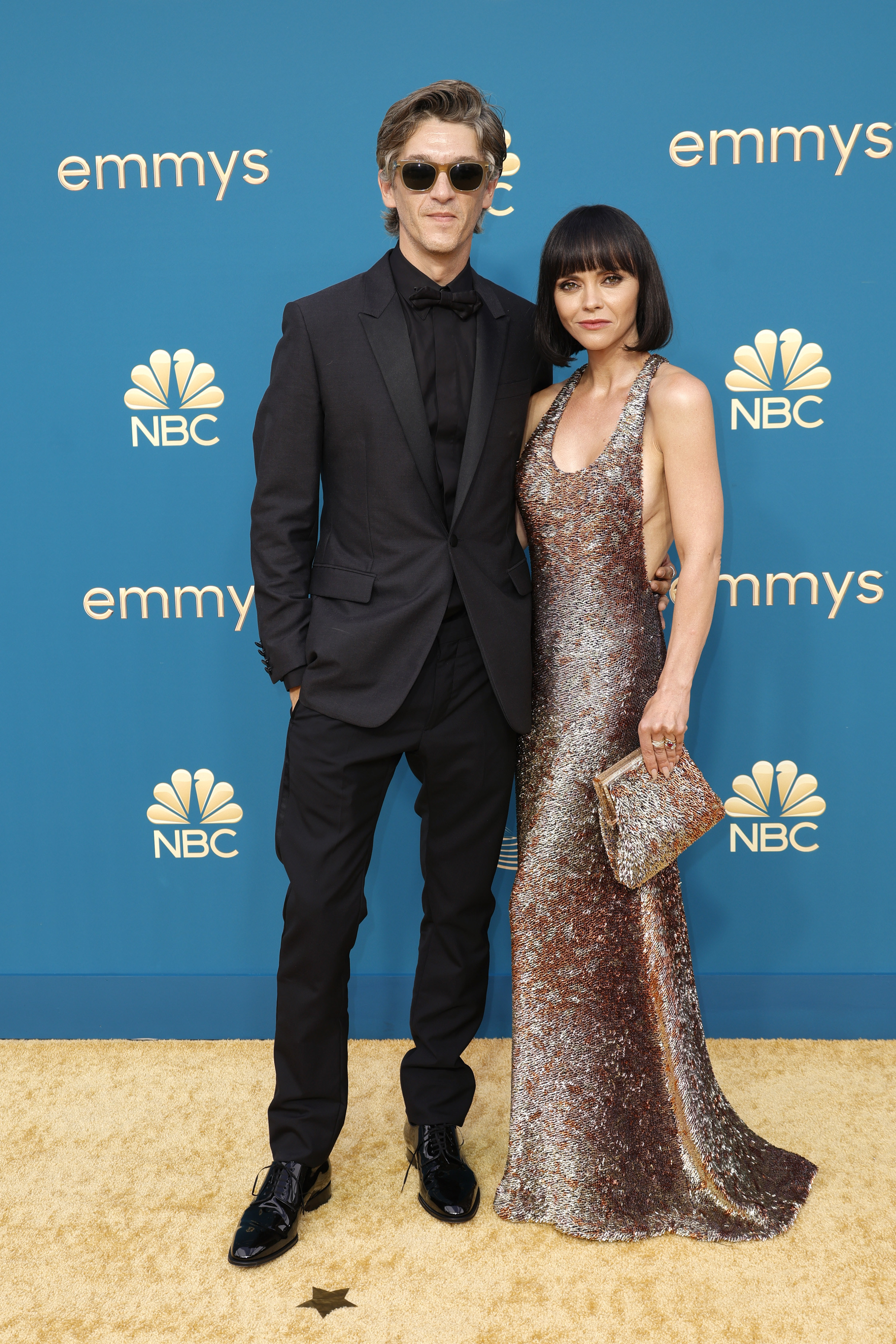 Christina Ricci in a backless sparkly metallic gown and Mark Hampton in a black suit and shirt