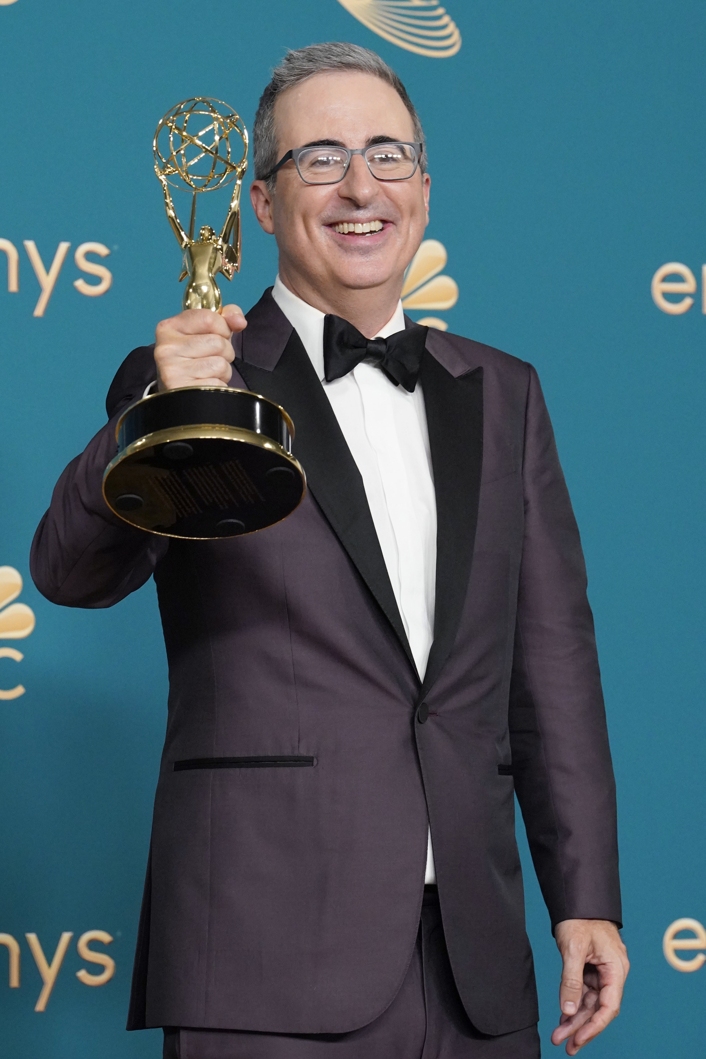 John Oliver smiling and holding an Emmy