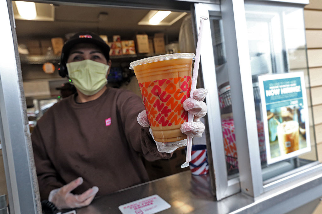Masked worker holding a Dunkin&#x27; iced coffee