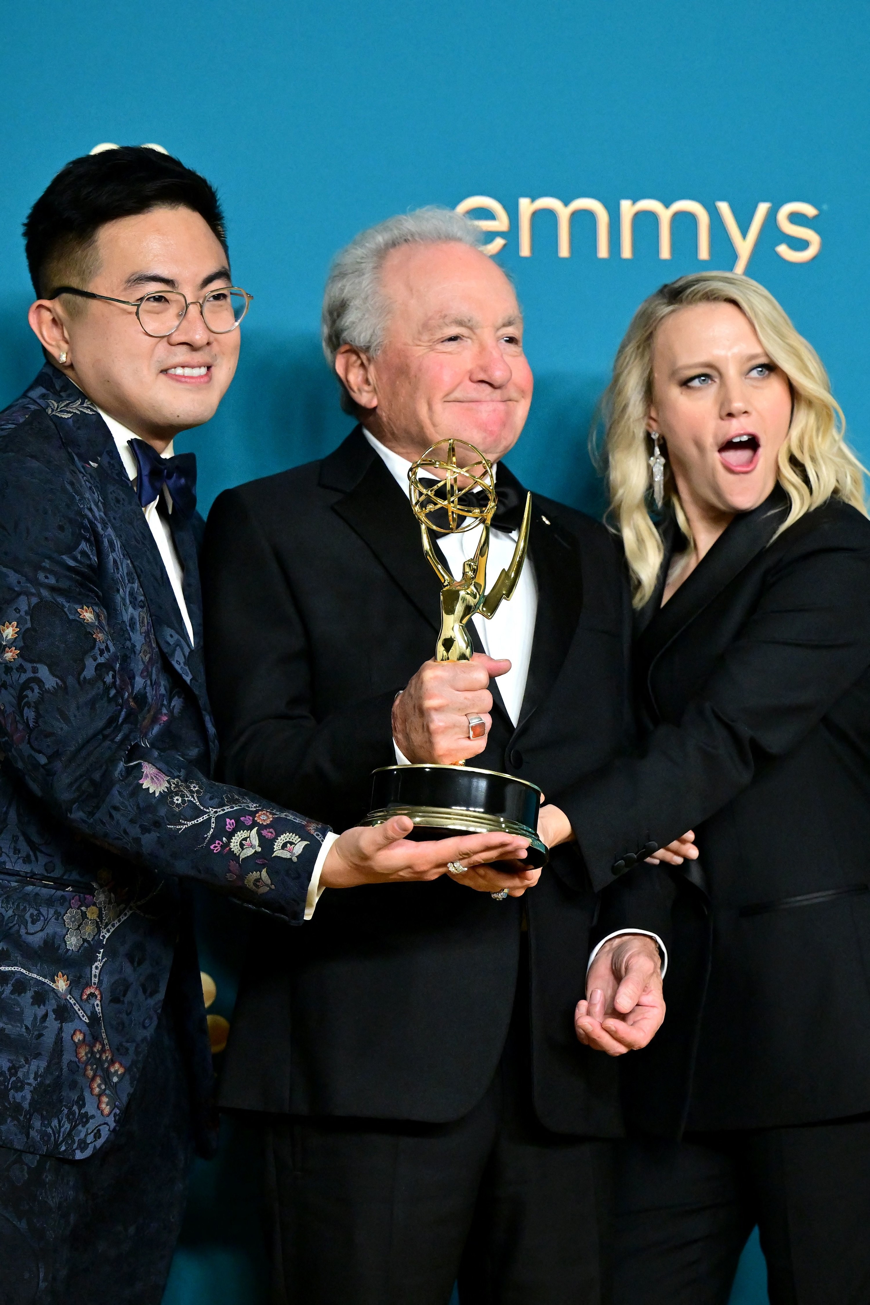 Lorne Michaels holding an Emmy and posing for a photo with two cast members