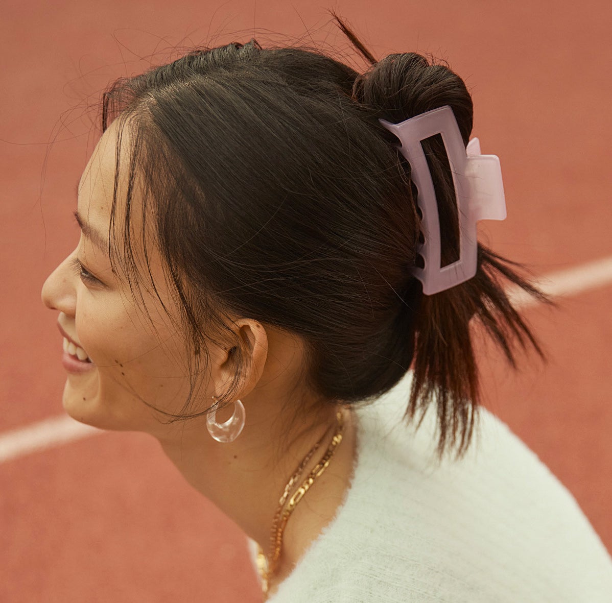 A person wearing a layered necklaces, a sweater, and the clip in their hair