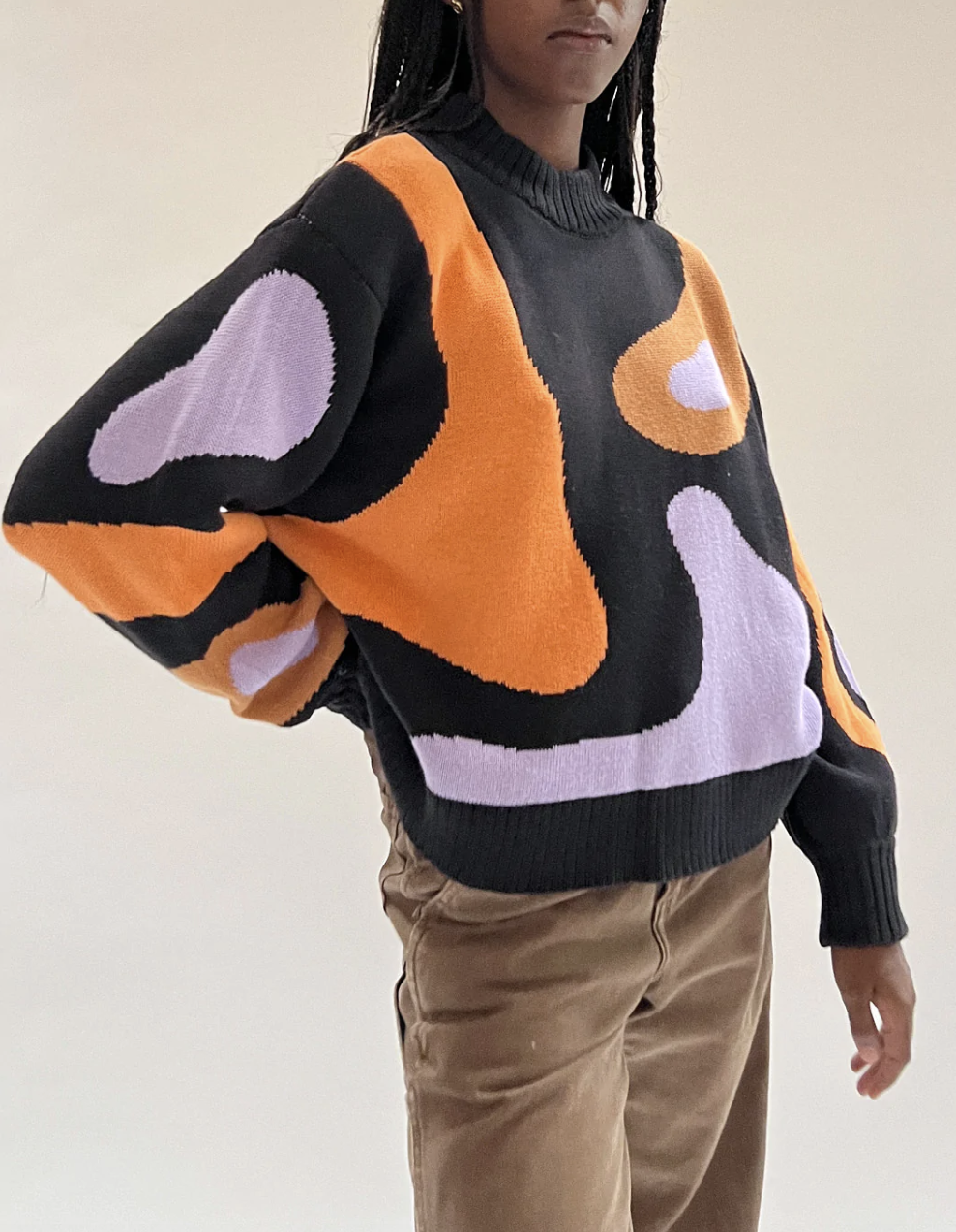 model wearing the black, purple, and orange crewneck sweater