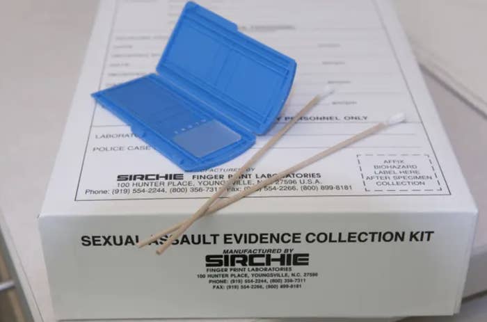 a sexual assault evidence collection kit: a white cardboard box with black text, on top is a small flat blue plastic case and two cotton swabs