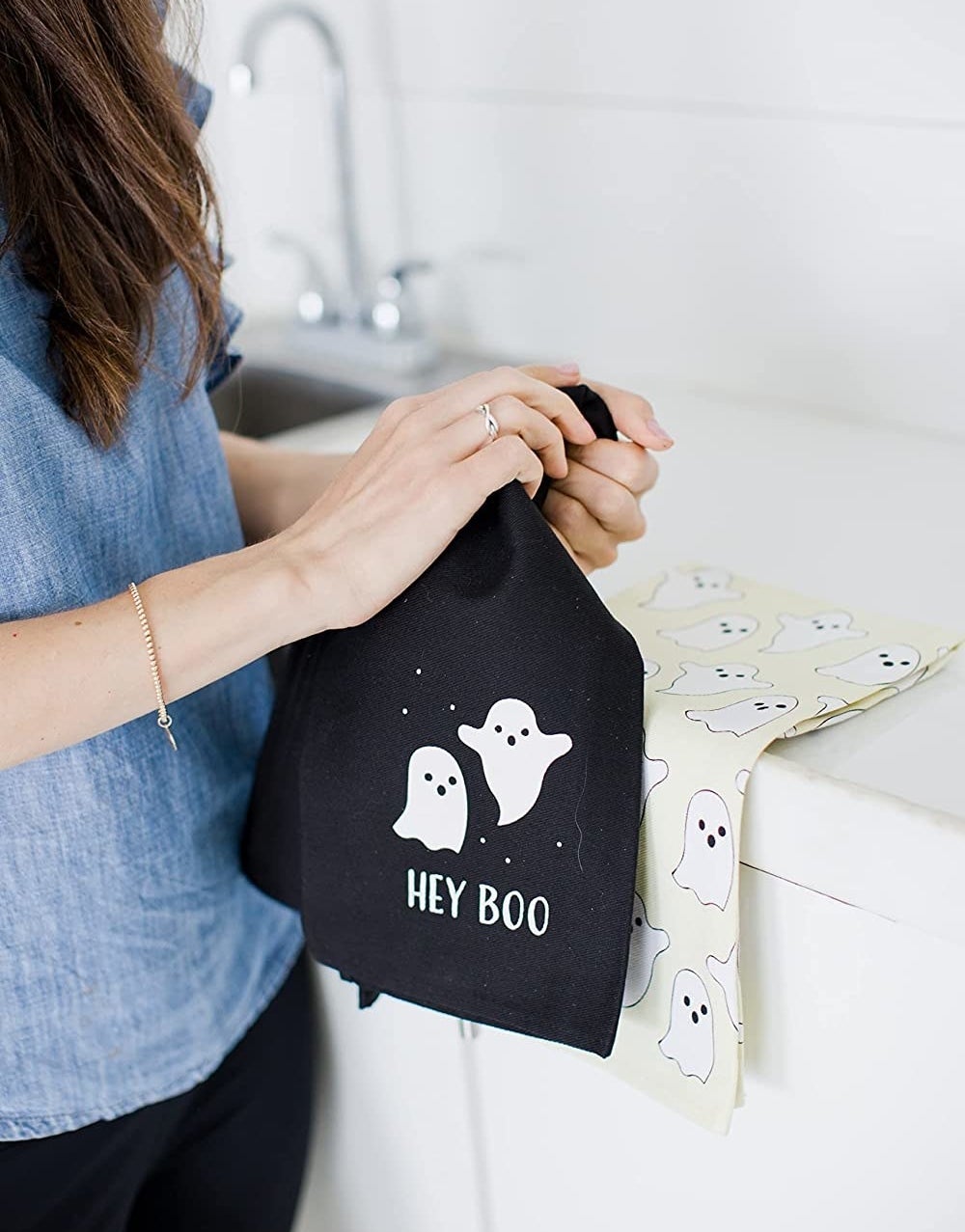 a person holding up a tea towel with a ghost on it that says hey boo