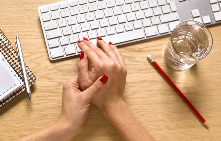 Closeup of a woman&#x27;s hands next to her computer