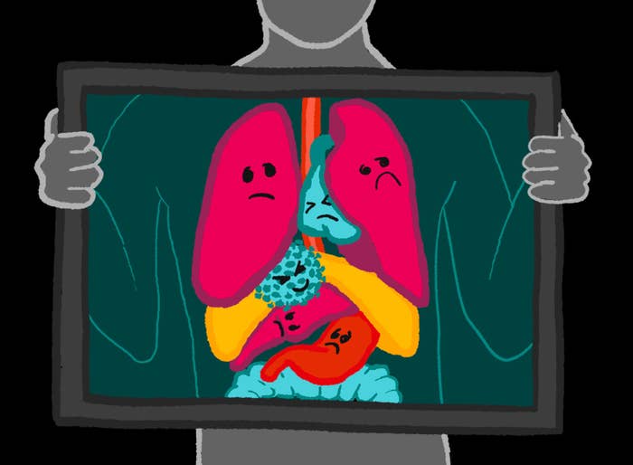 An illustration of a person holding an X-Ray frame in front of their torso. The organs have frowning faces. There is a coronavirus cell in the body with a mean face