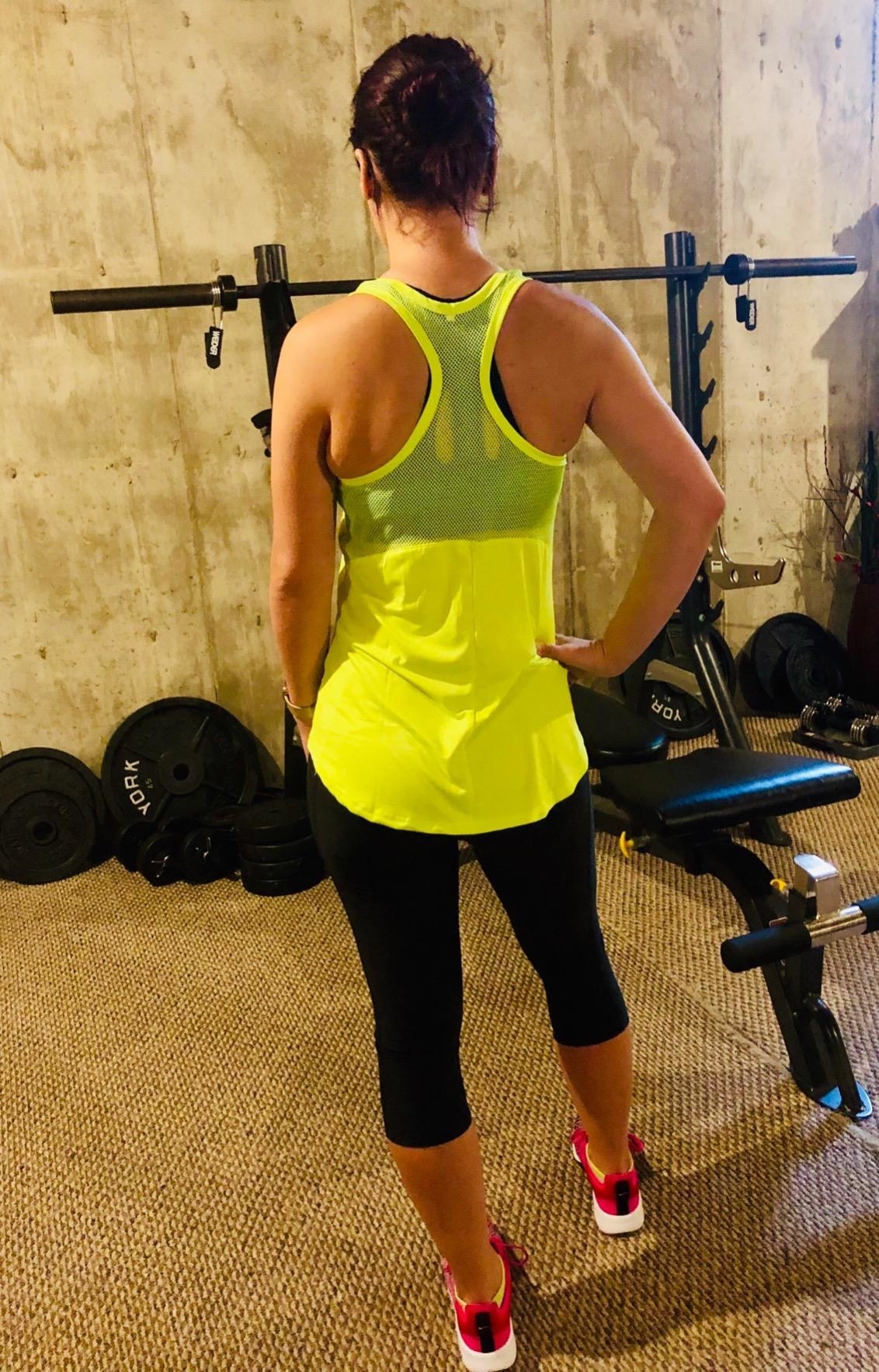 Reviewer wears neon green ventilated tank top with matching black leggings