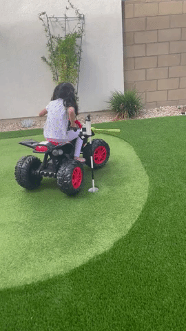 A child riding the ATV in the backyard
