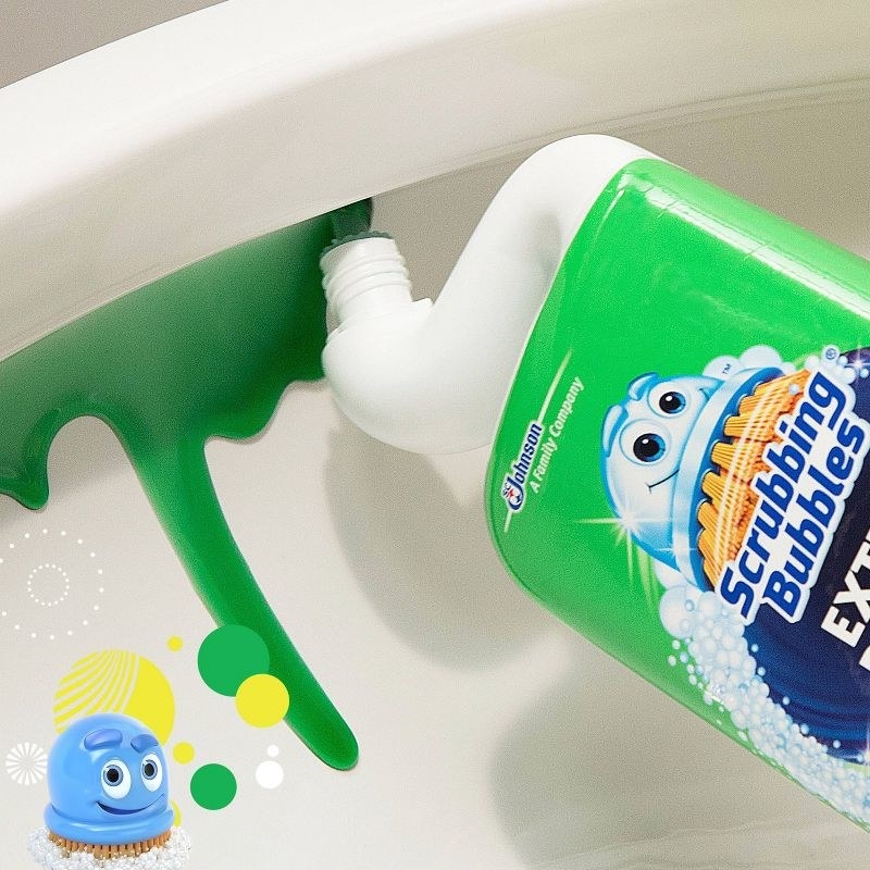 a photo of the curved necked bottle being used to apply green cleaner around the rim of a toilet bowl. the scrubbing bubbles mascot is in the lower left corner