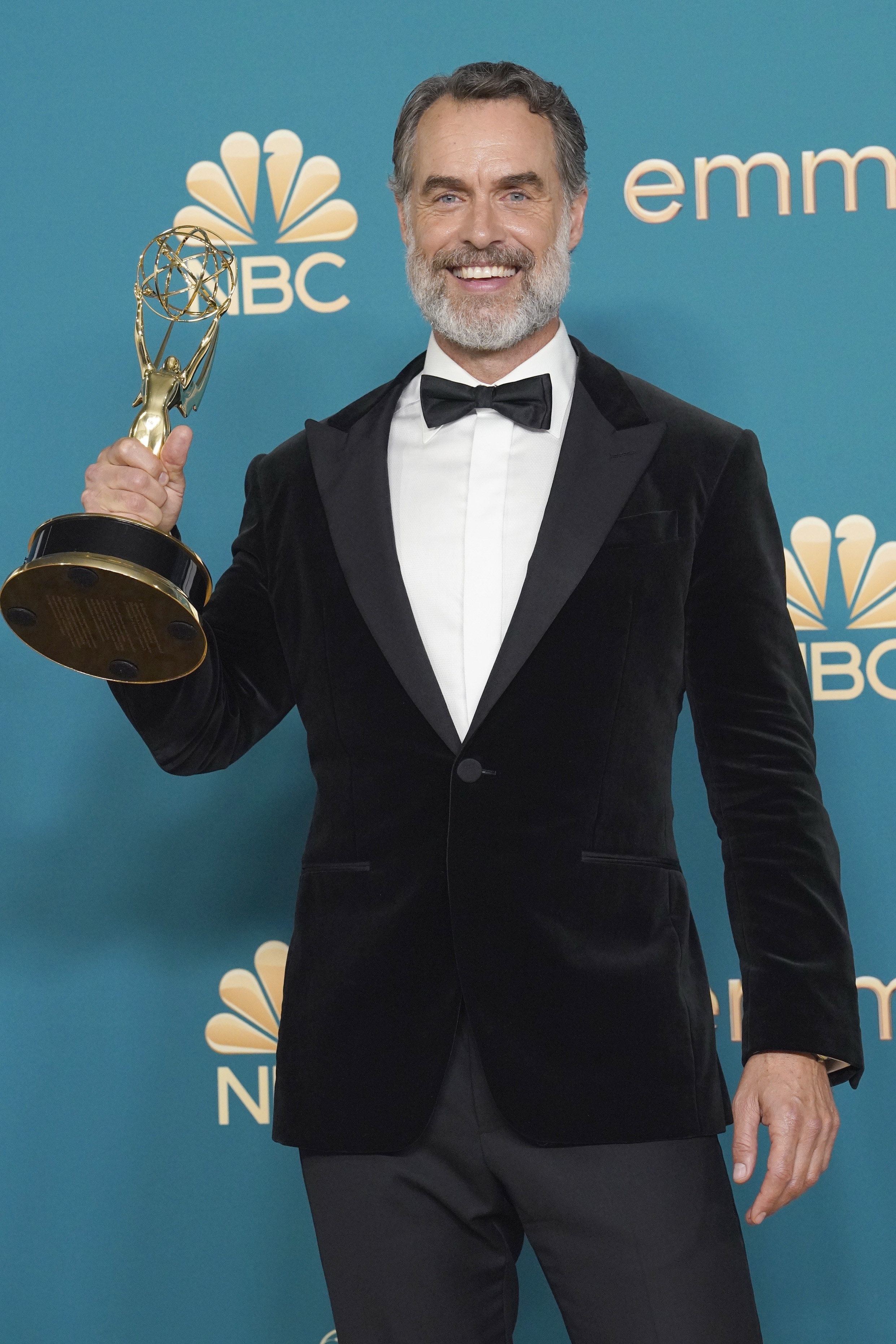 Murray Bartlett smiling and holding his Emmy