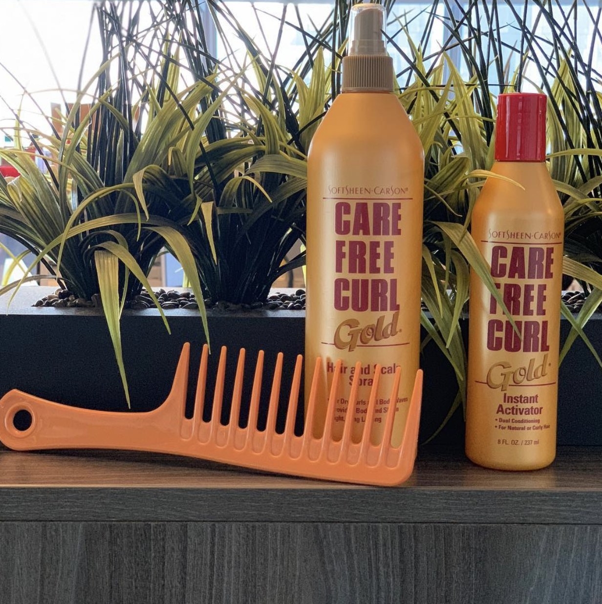 A bottle of curl activator and hair spray with an orange comb