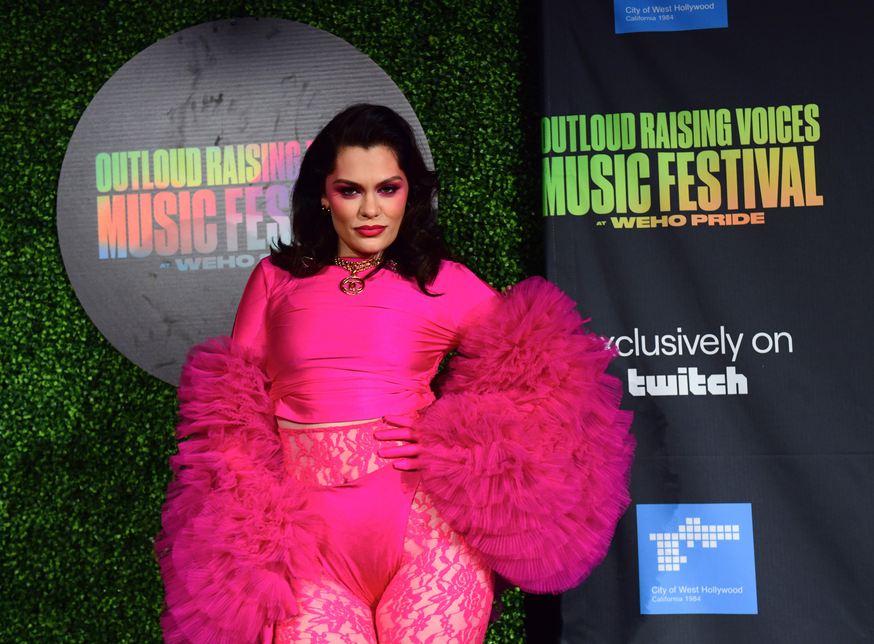 Jessie J wearing a bright pink outfit with large ruffled sleeves and matching dramatic pink eye make up