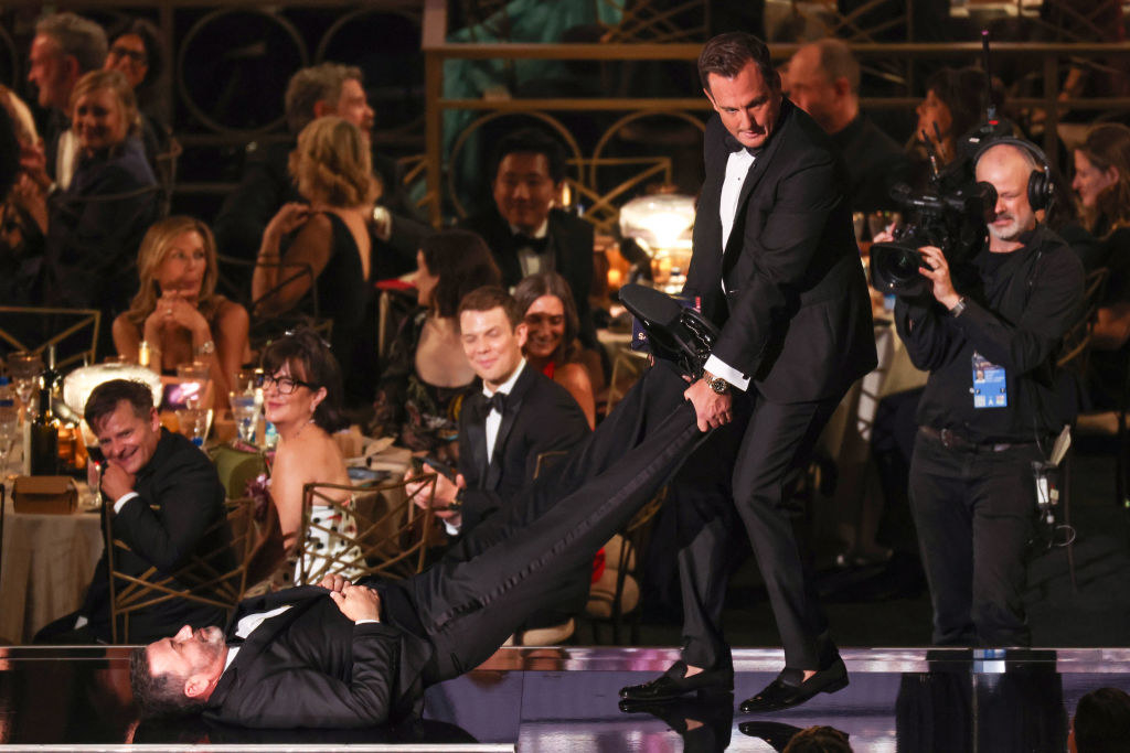 Will Arnett pulling Jimmy Kimmel, who is lying on the ground, by the legs