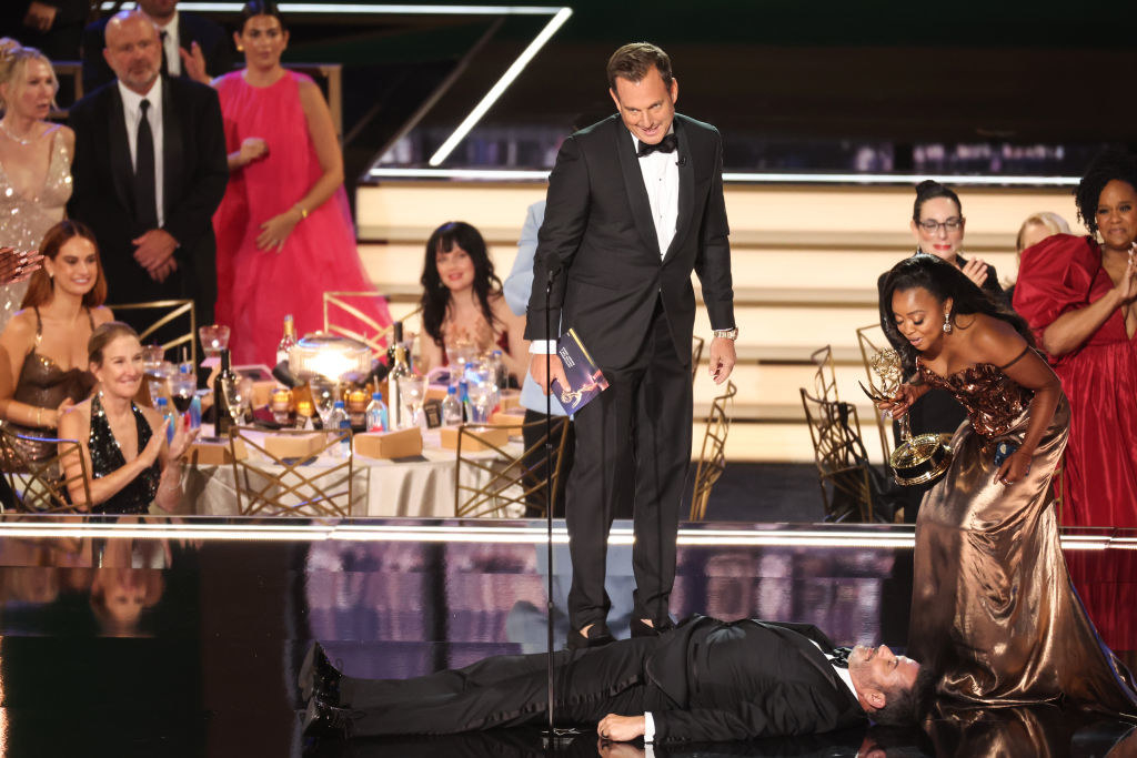 Jimmy Kimmel lying down while Quinta holds her Emmy